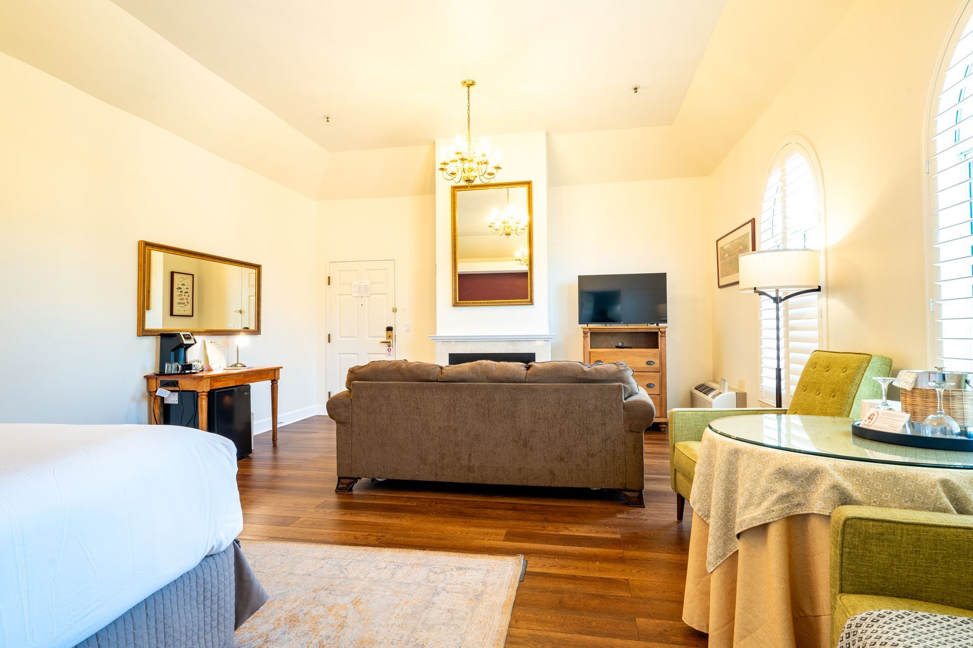 Spacious hotel room with a couch, table, TV, and large window.