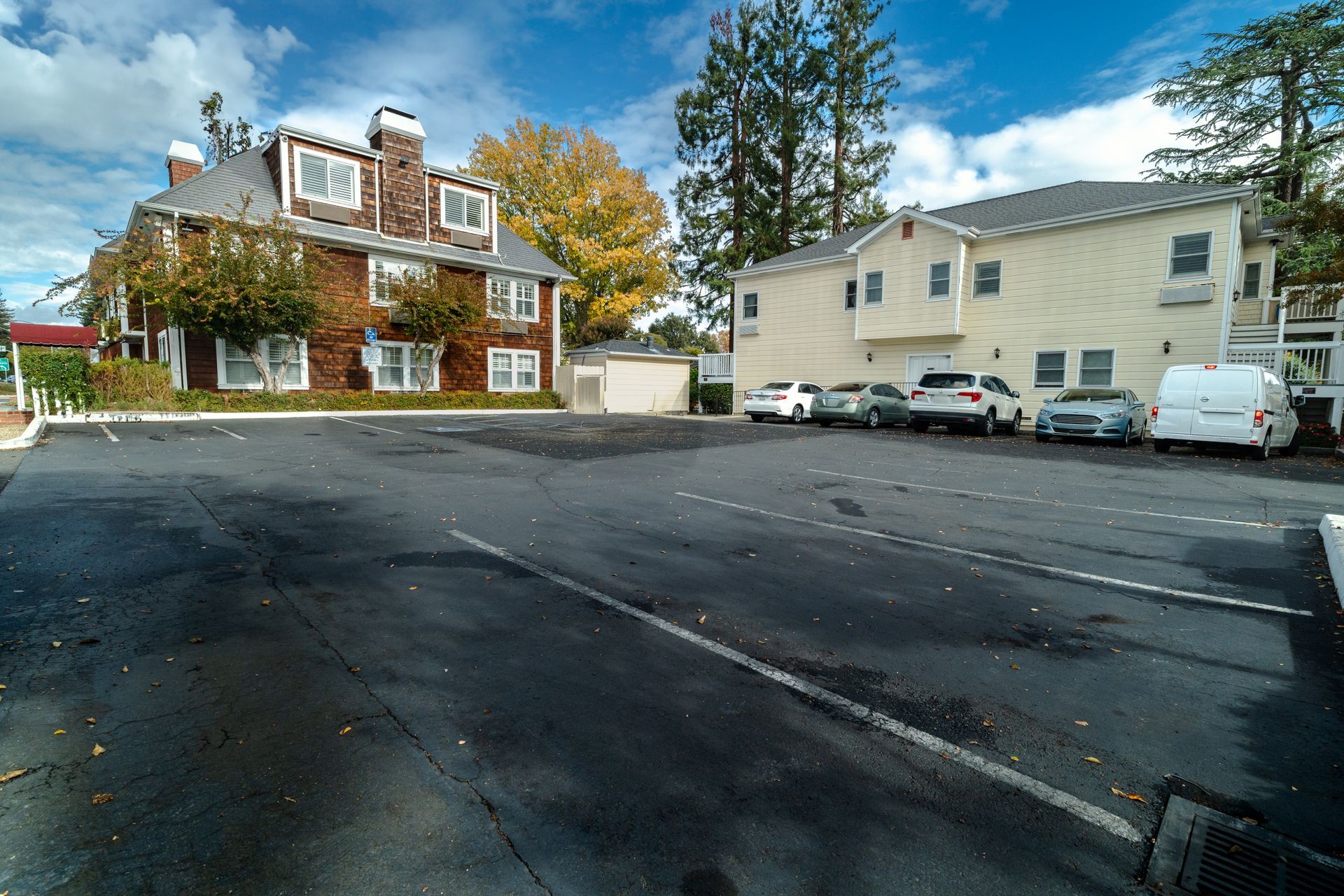Parking lot with cars in front of two-story buildings on a sunny day.