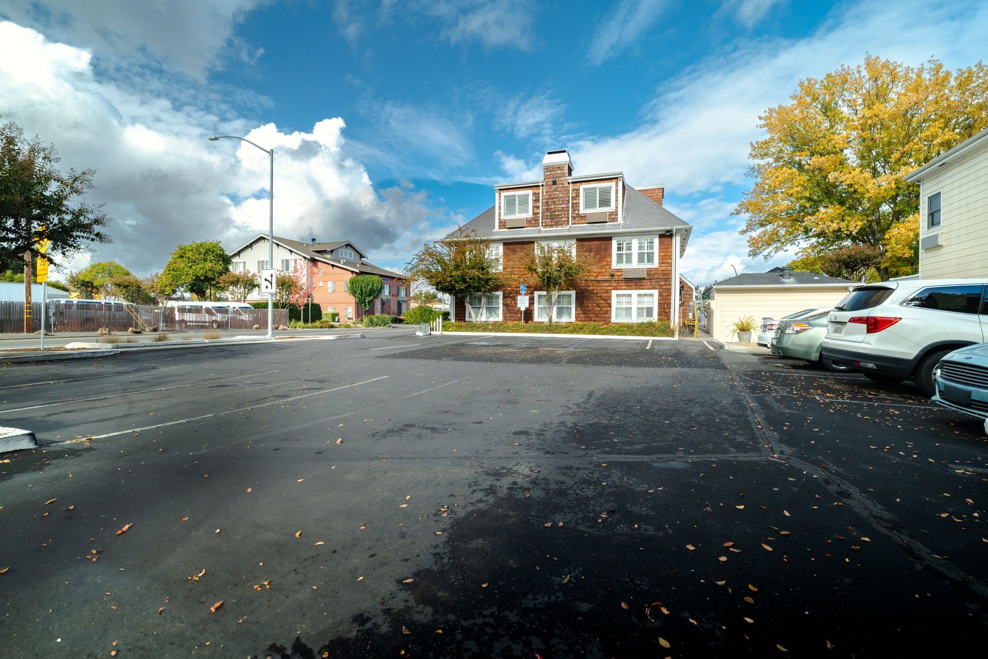 Parking lot with cars in front of a brick building under a cloudy sky.