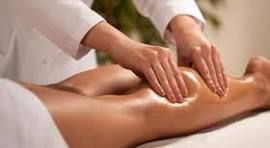 Hands massaging a person's leg with oil in a professional setting.