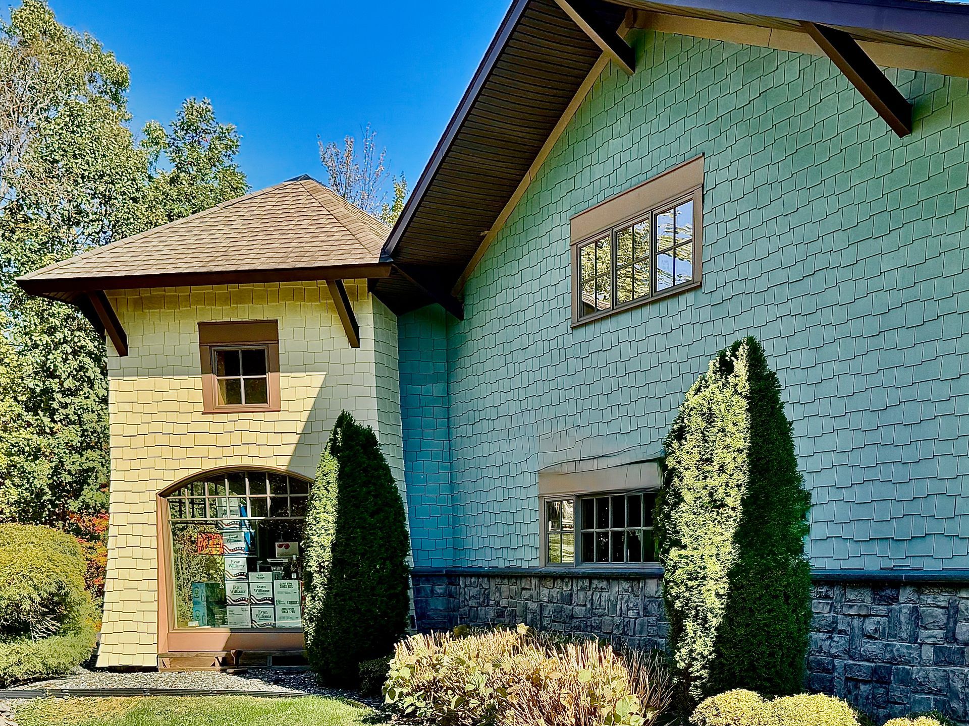 House exterior with turquoise siding and stone details; small windows and a decorative door.