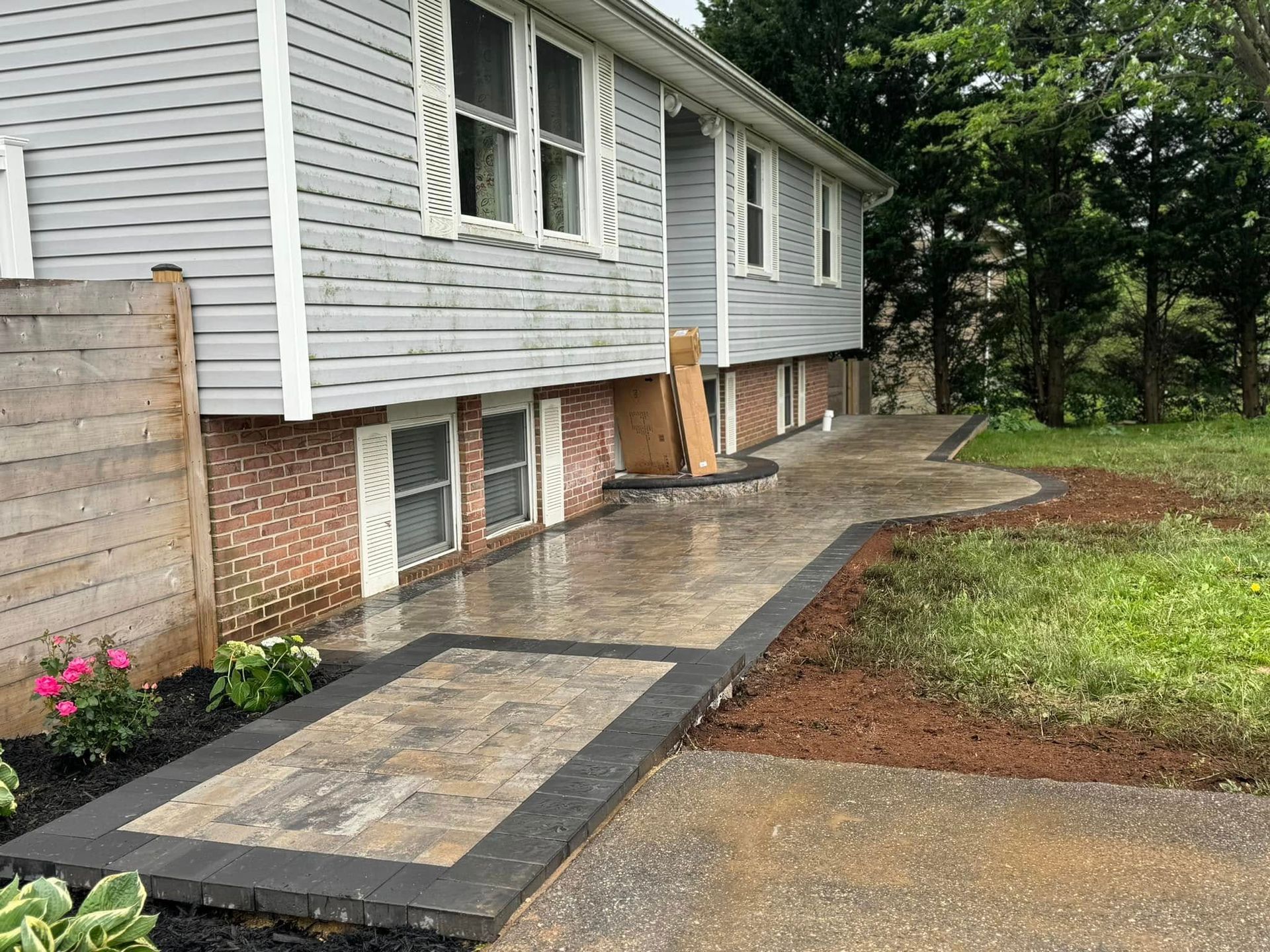 A white house with a brick fence and a concrete walkway in front of it.