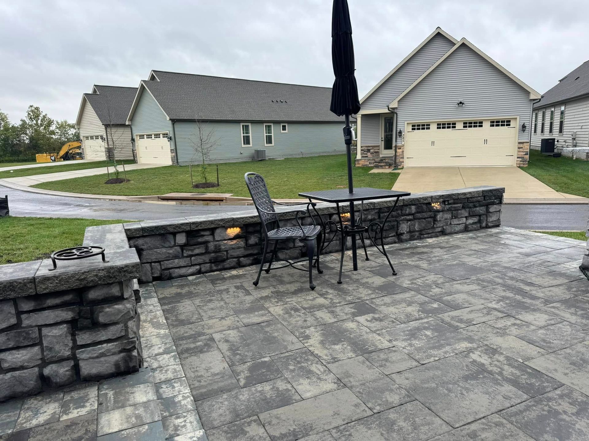 A patio with a table and chairs and an umbrella in front of a house.