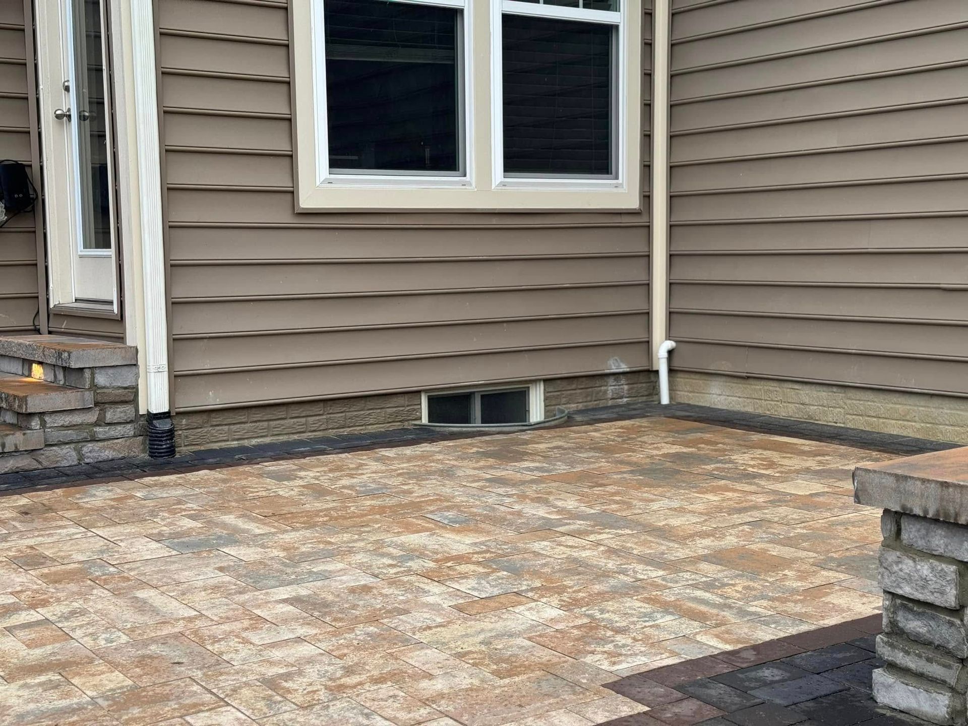 There is a patio in front of a house with a window.