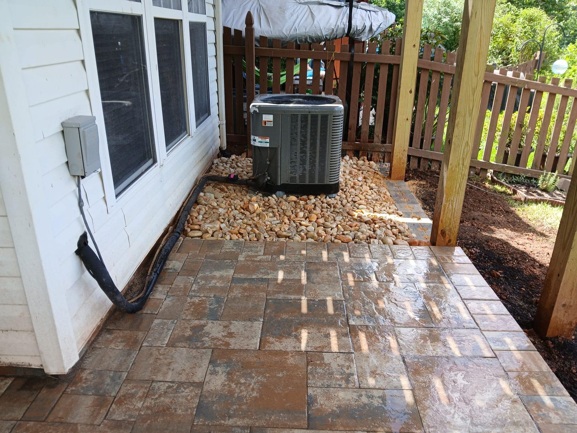An air conditioner is sitting on a patio next to a house.