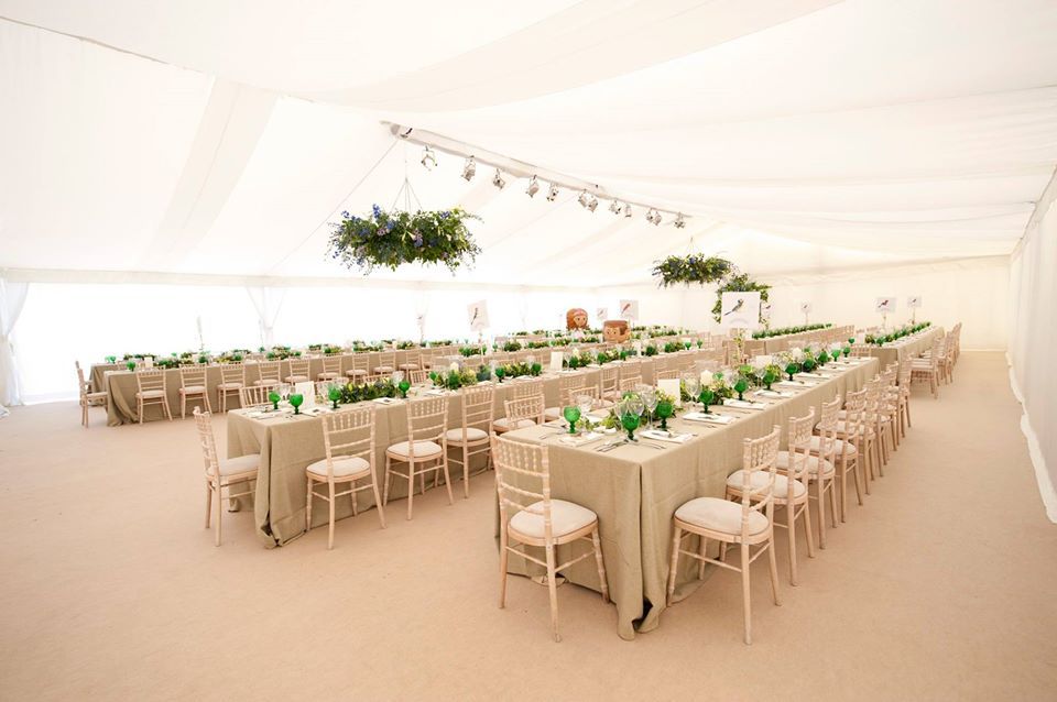 A large tent with tables and chairs set up for a wedding reception.