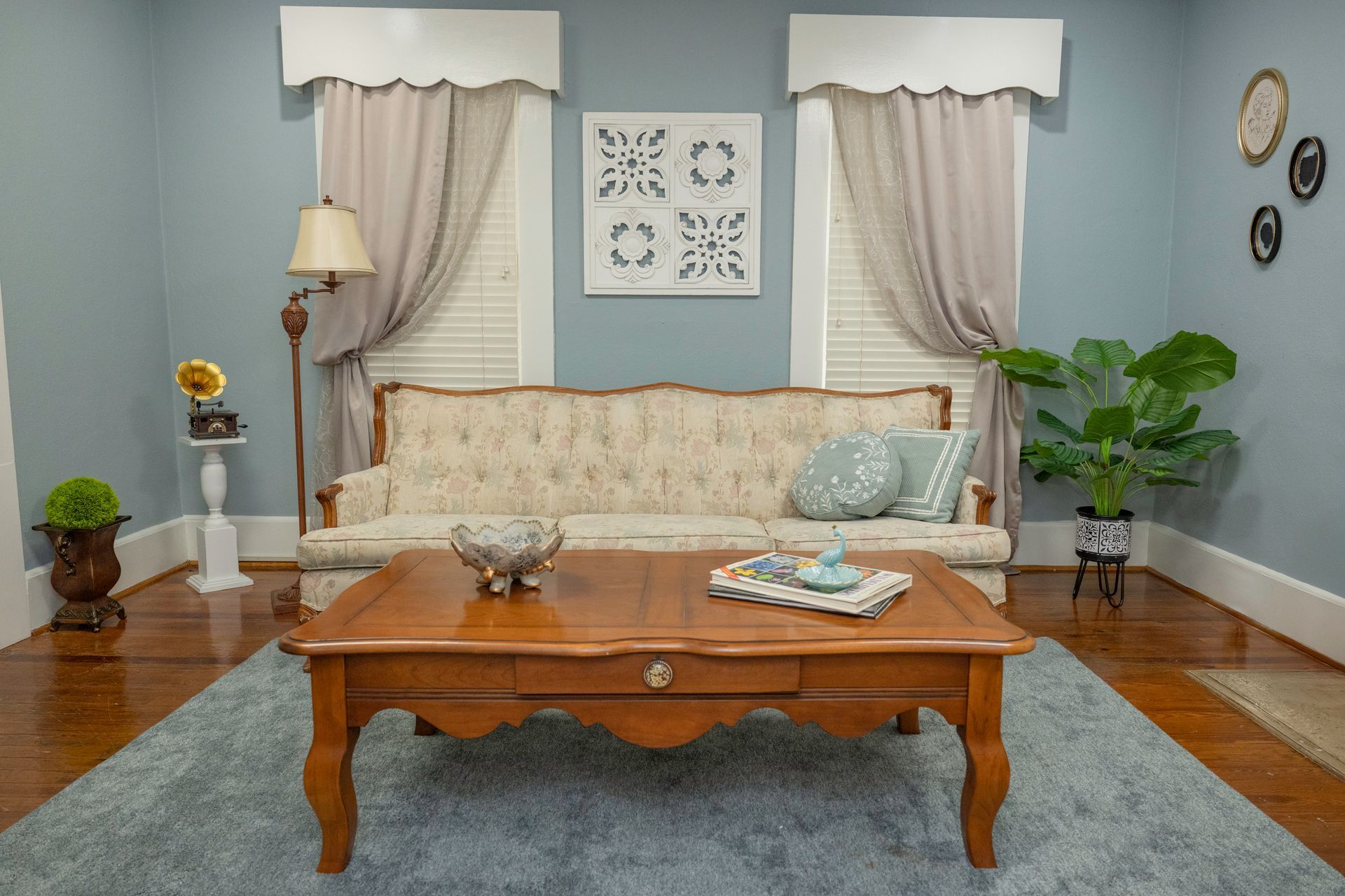 Living room with blue walls, beige couch, wooden coffee table, and large houseplant.