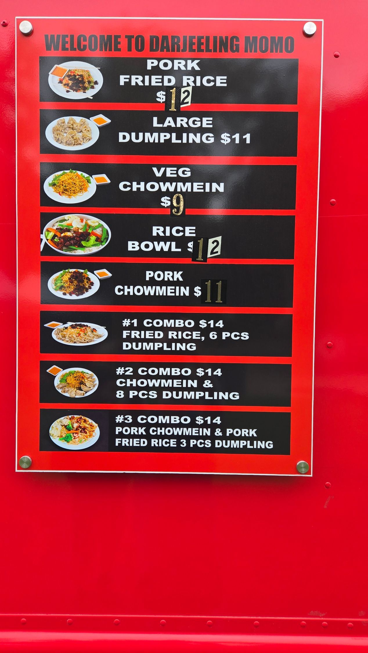 Menu board on a red food truck, featuring pork fried rice, dumplings, and other dishes with prices.