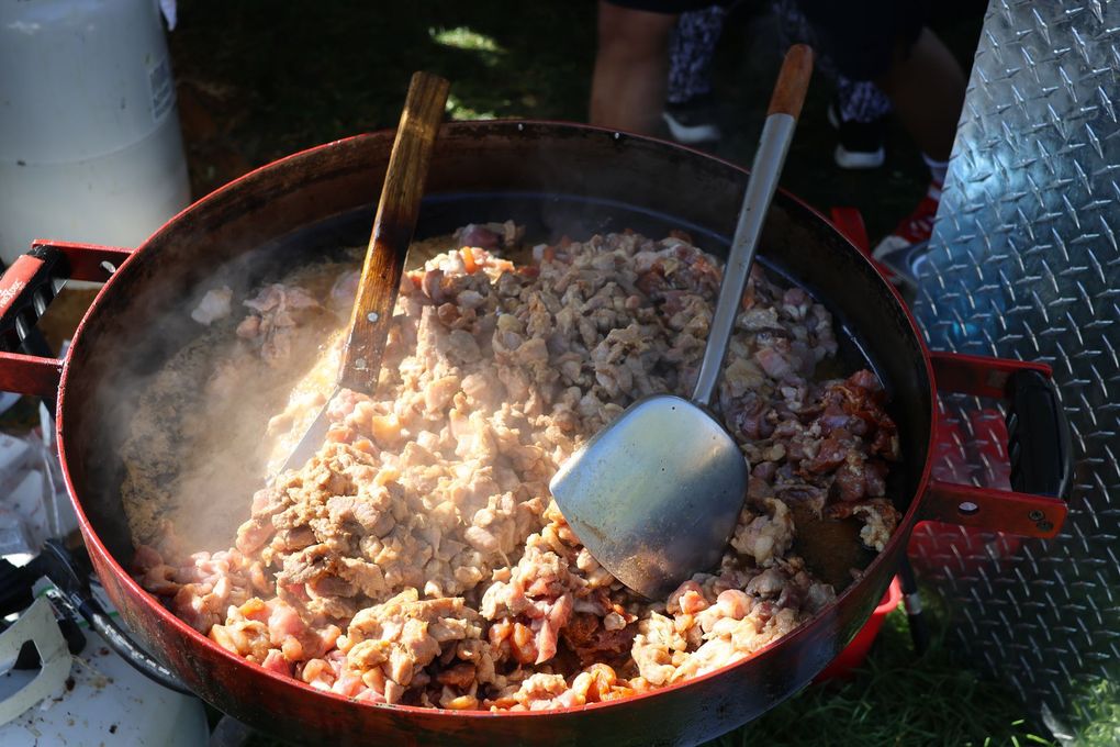 Large pot of steaming cooked meat with two serving utensils.