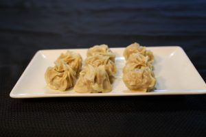 Dumplings on a white rectangular plate; set against a black background.