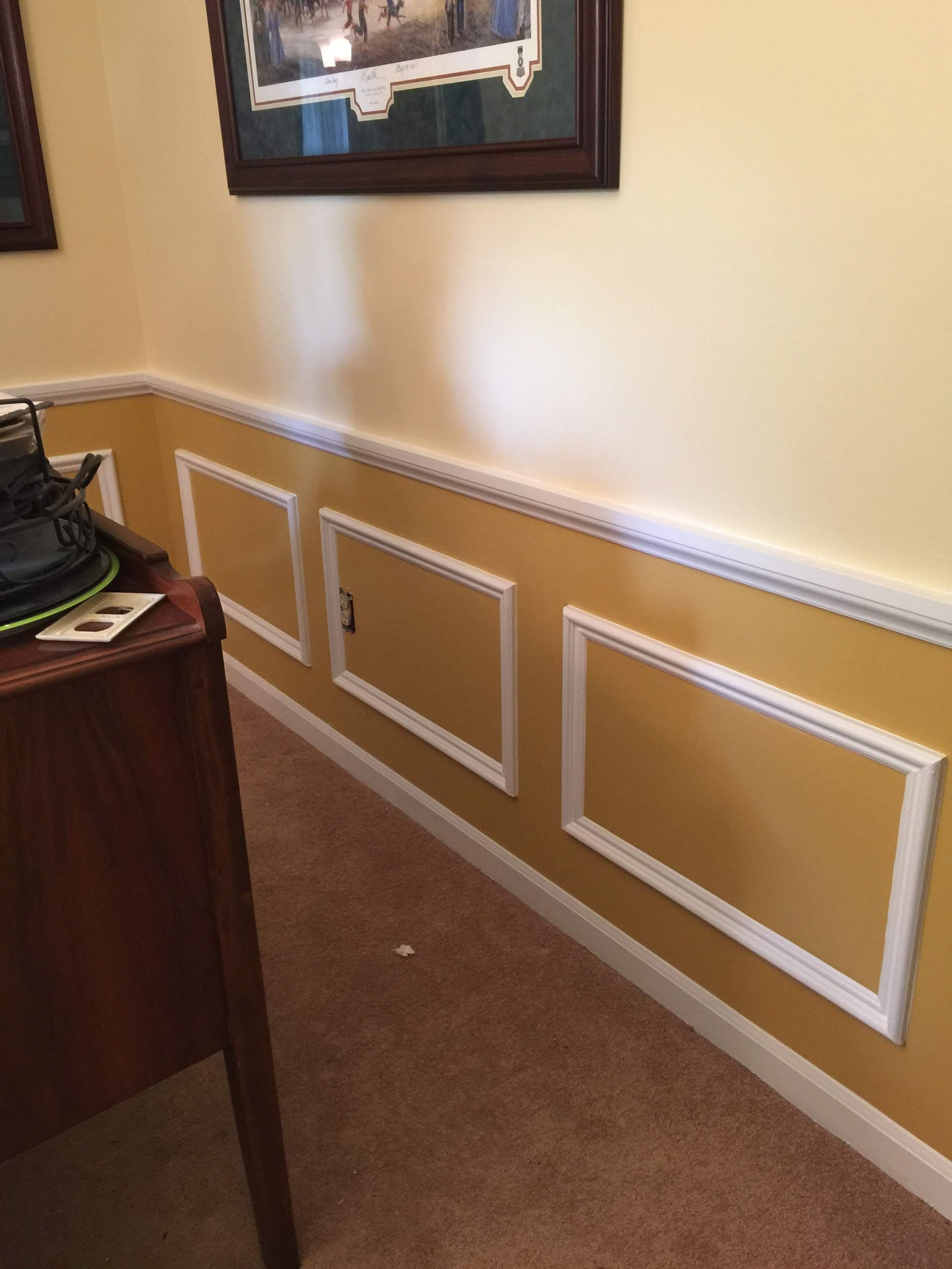 Yellow wall with white molding, three rectangular panels, and brown carpet.