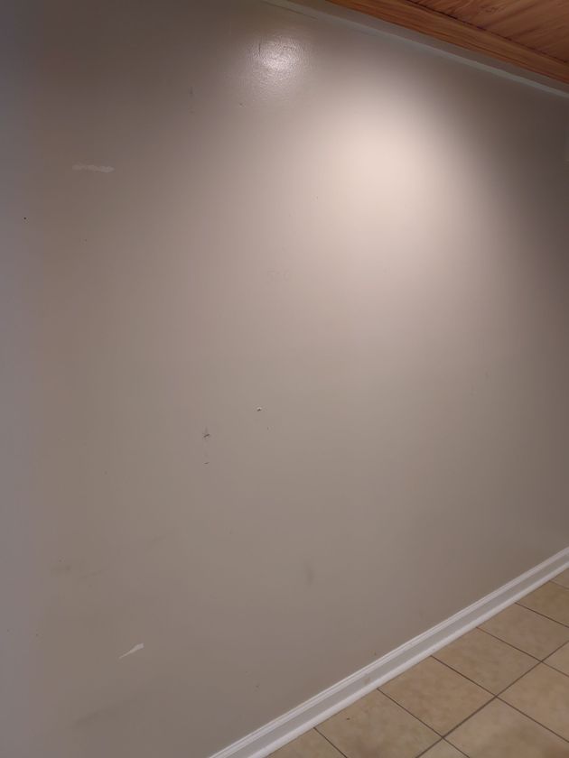 Beige painted wall with a spotlight, white baseboard, and light-colored tiled floor.