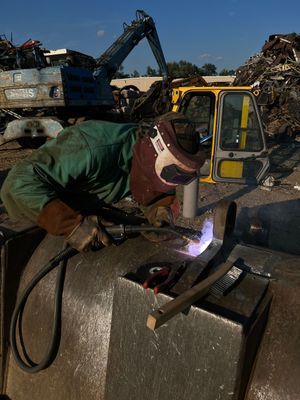 A man wearing a welding mask is working on a piece of metal