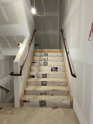 A staircase in a building under construction with a wooden railing.