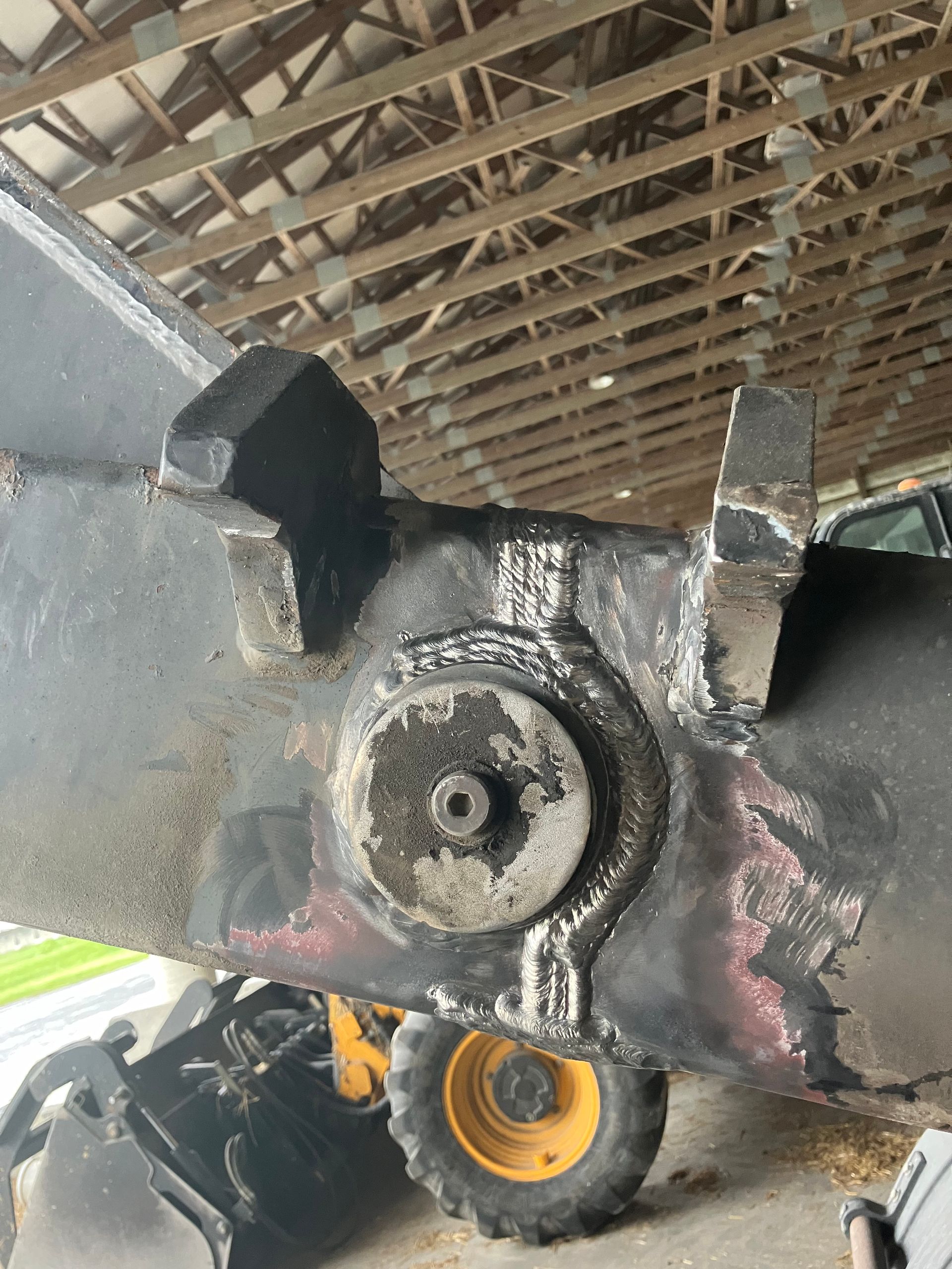 A close up of a machine in a garage with a yellow tire.