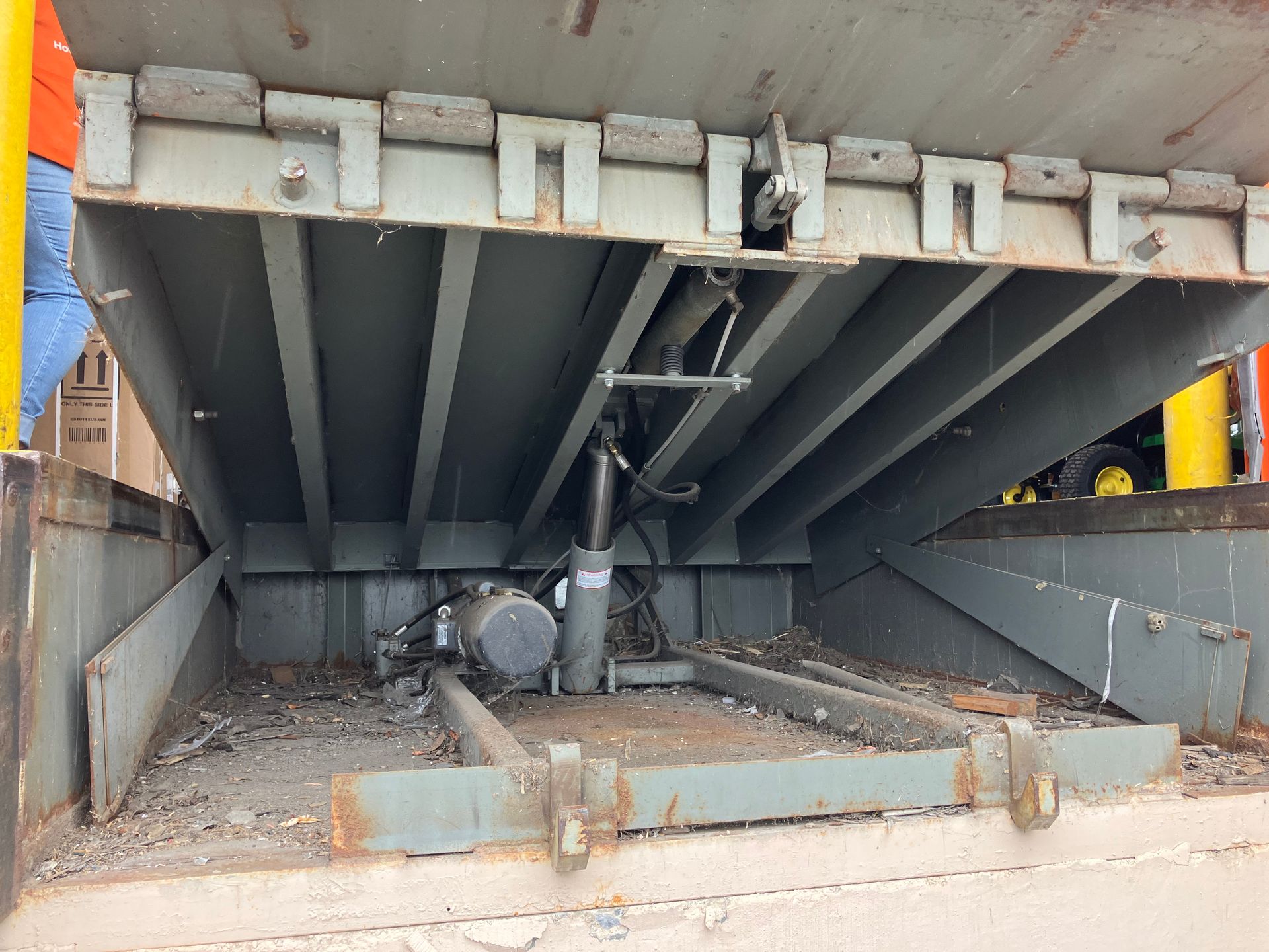 A large metal structure is sitting on the ground under a bridge.