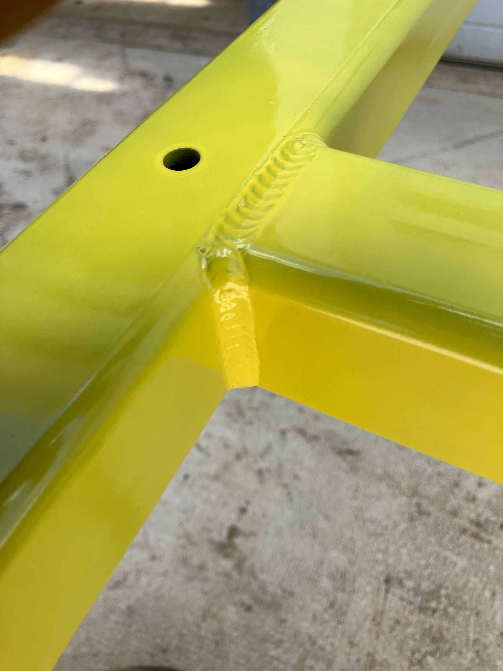 A yellow metal frame with a hole in the middle is sitting on the ground.