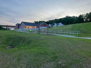 A row of bike racks in a grassy field with a house in the background.