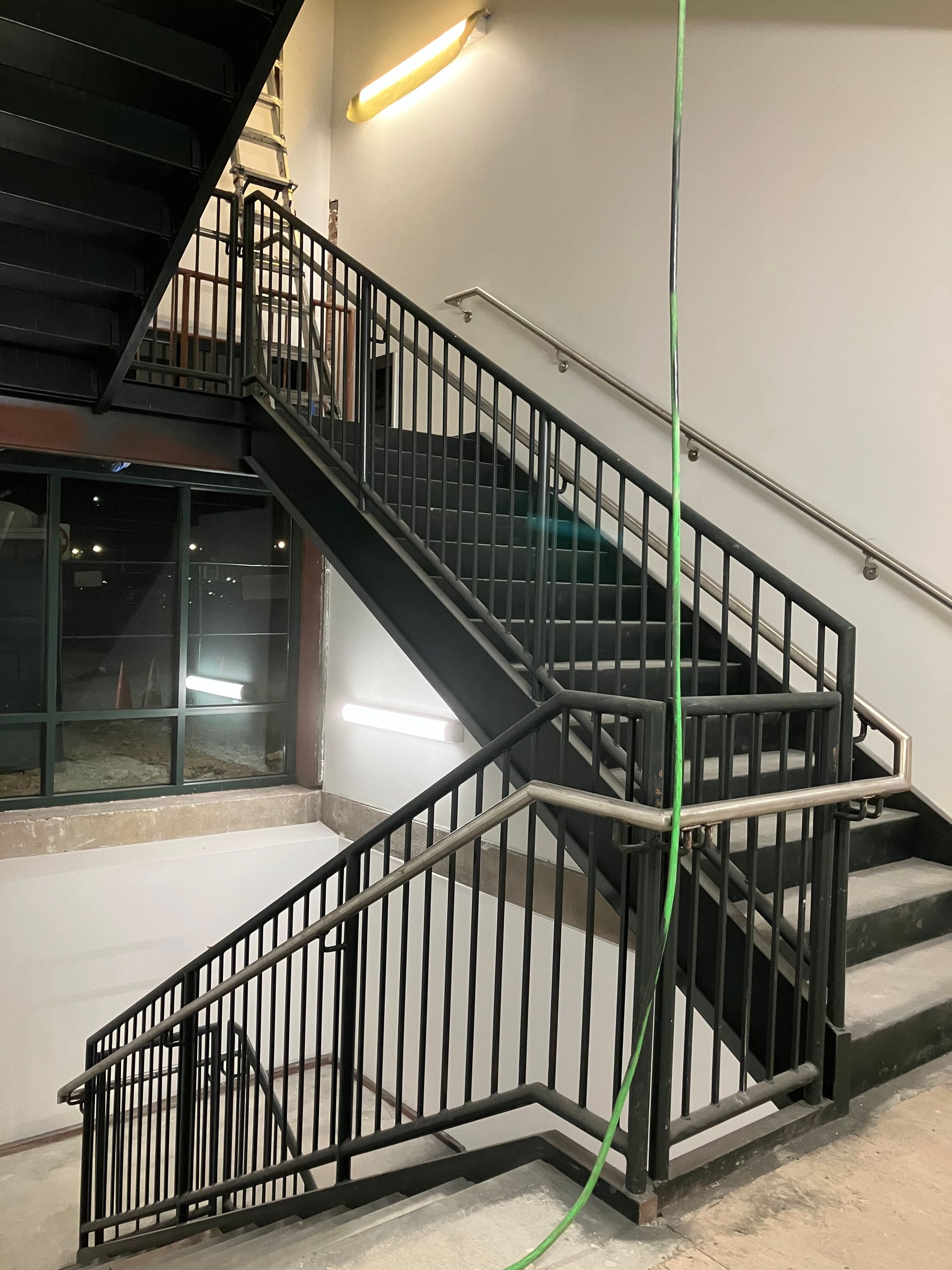 A black metal staircase with a green hose hanging from the railing.