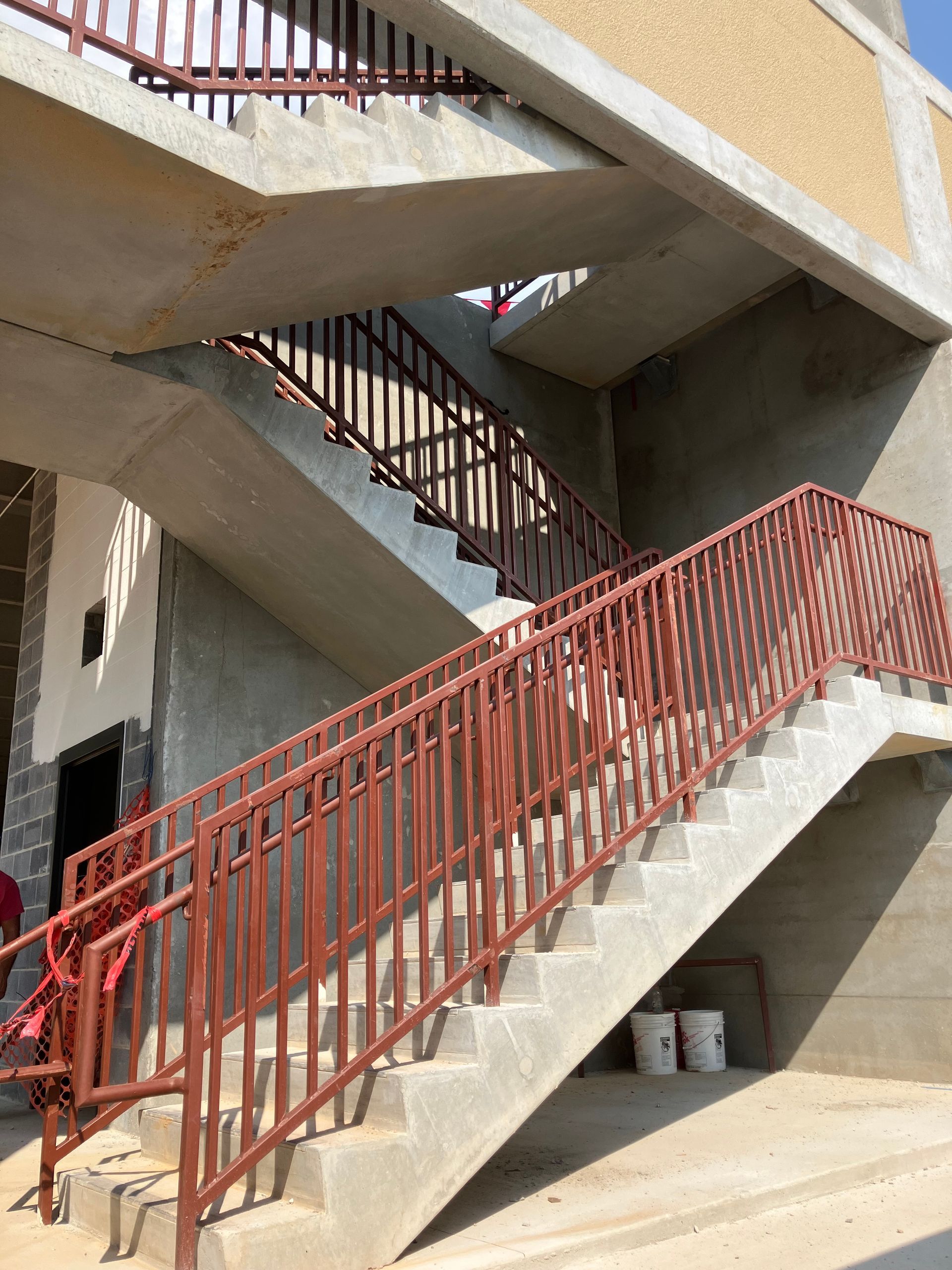 A staircase with a red railing is under construction