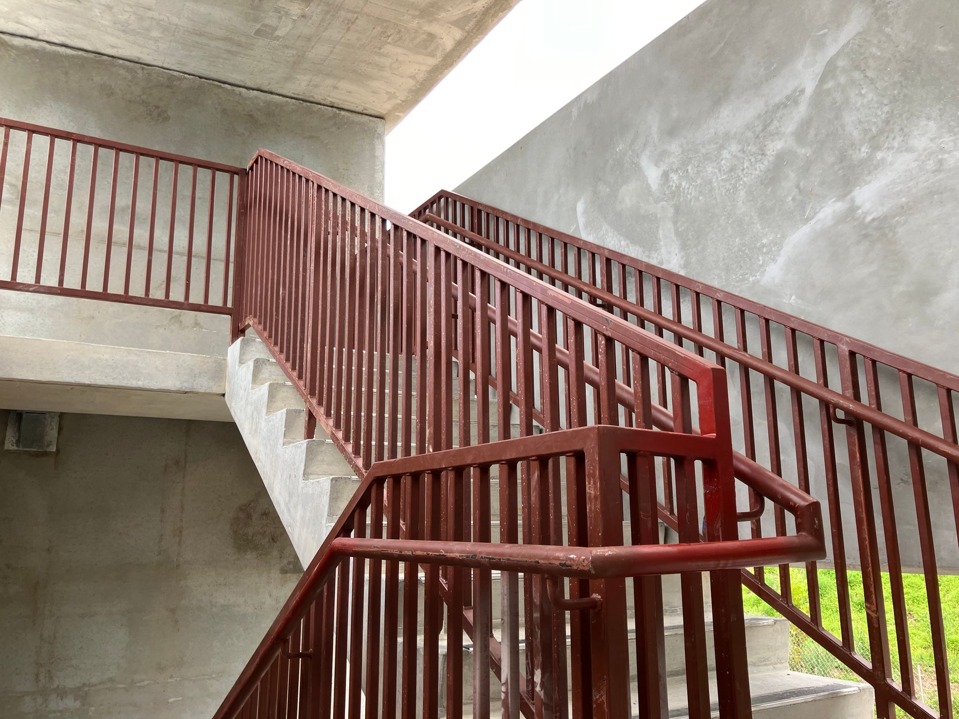 A staircase with a red railing and a concrete wall.