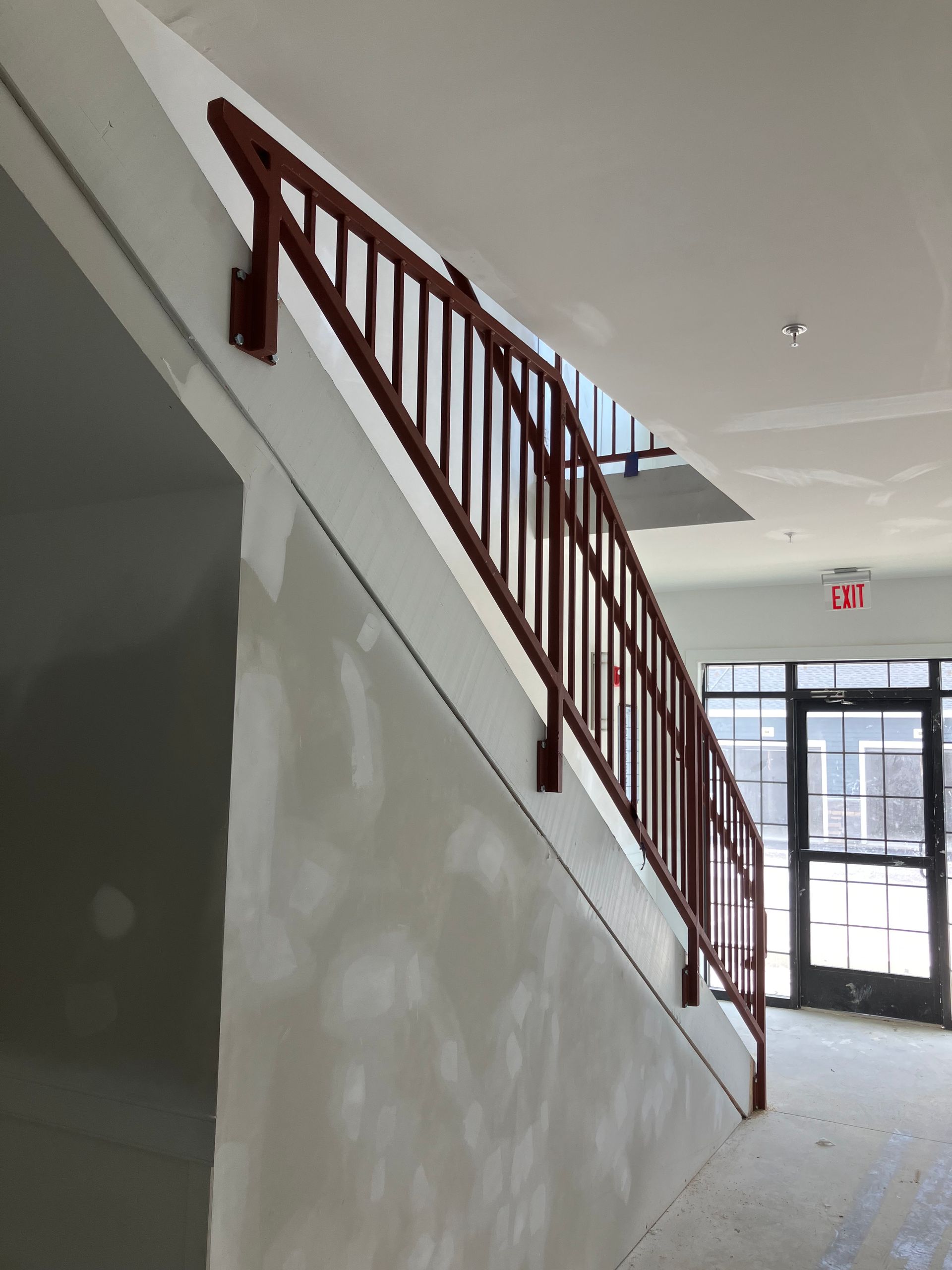 A staircase with a red railing and a red exit sign