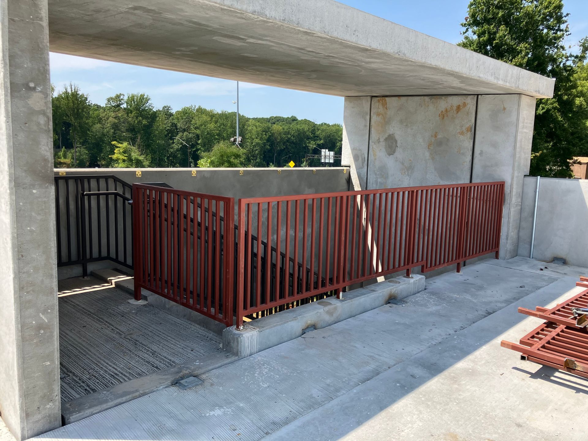A red railing is surrounding a staircase in a parking garage.