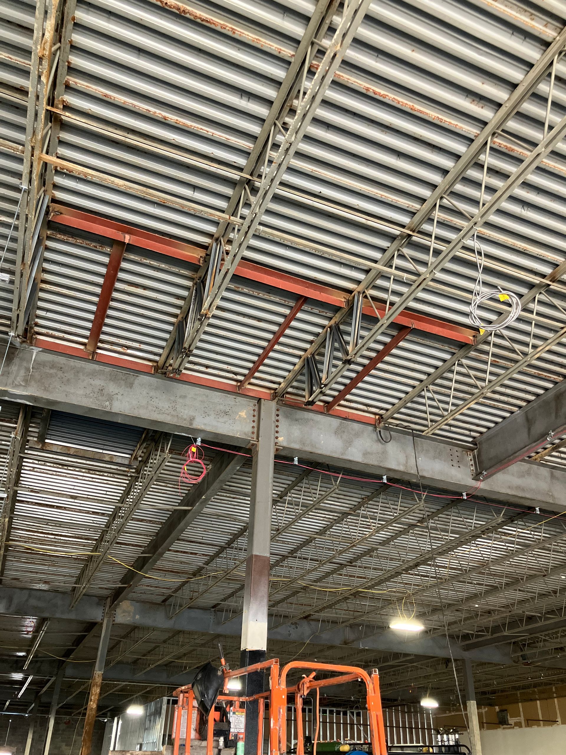 A forklift is sitting on top of a metal ceiling in a warehouse.