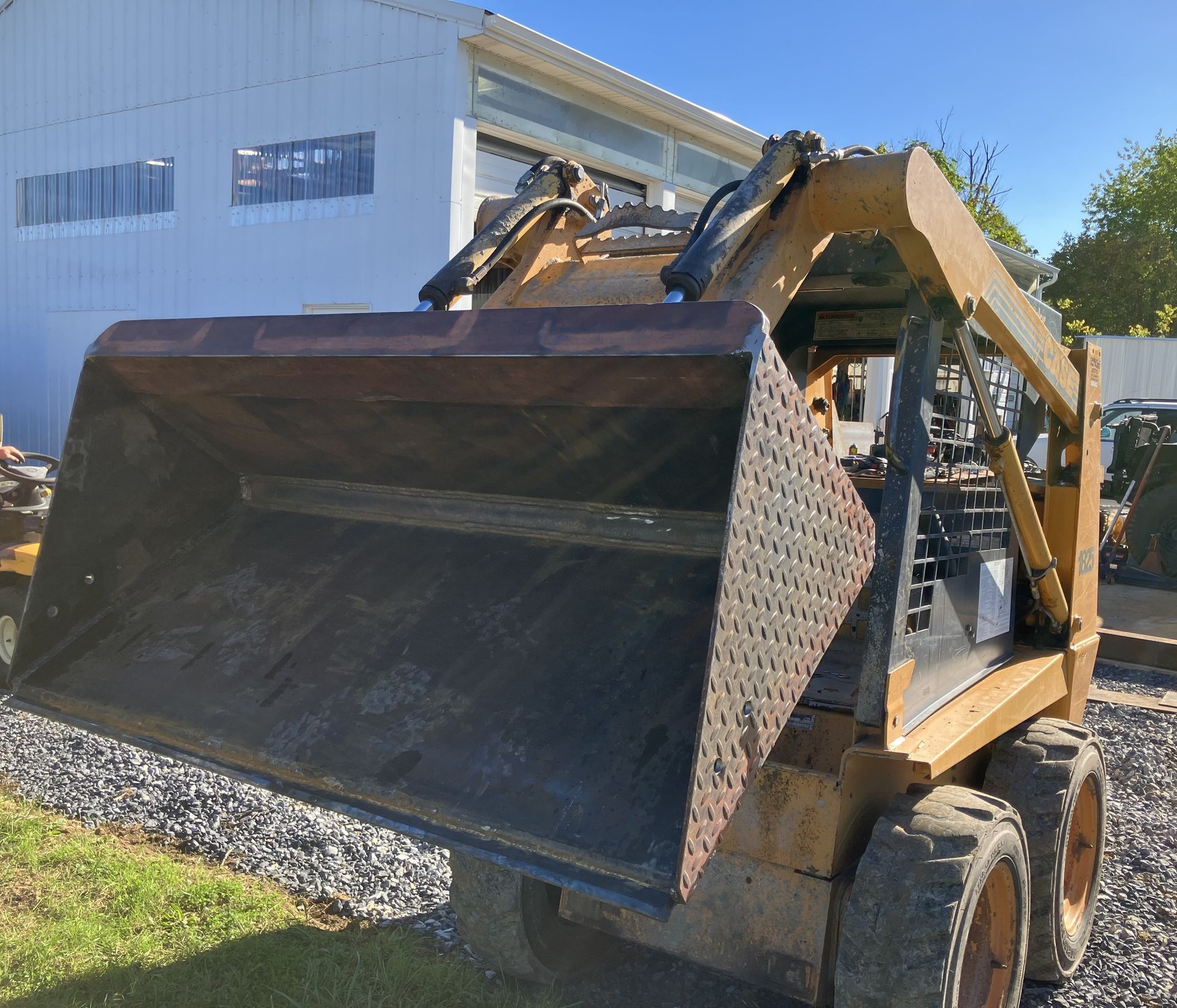 A bulldozer with a large bucket is parked in front of a white building
