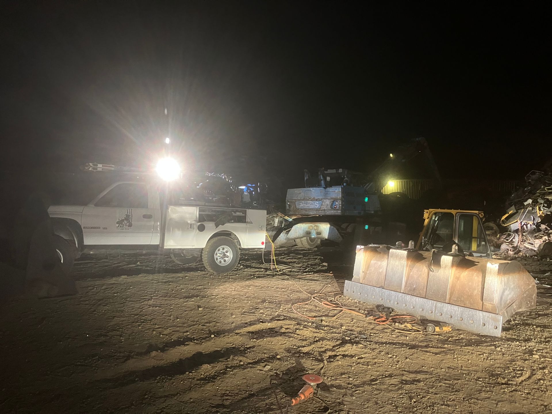 A truck is parked next to a bulldozer at night.