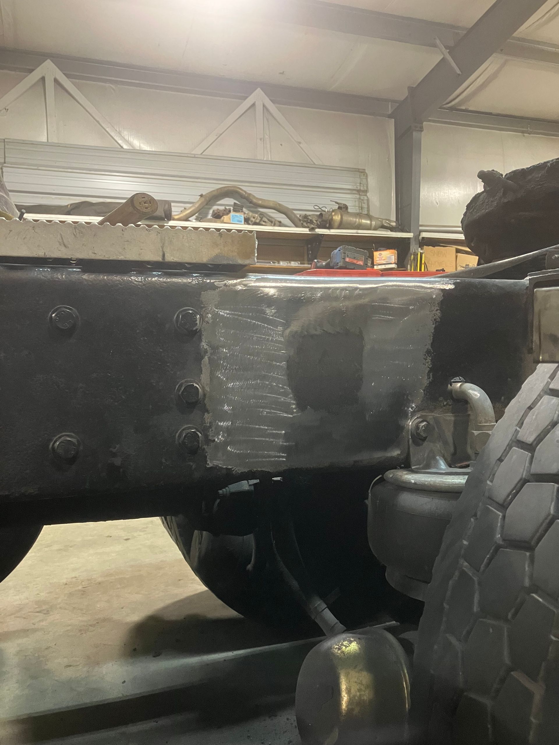 A black truck is parked in a garage with a tire on the ground