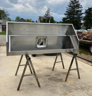 A large stainless steel item is sitting on wooden trestles