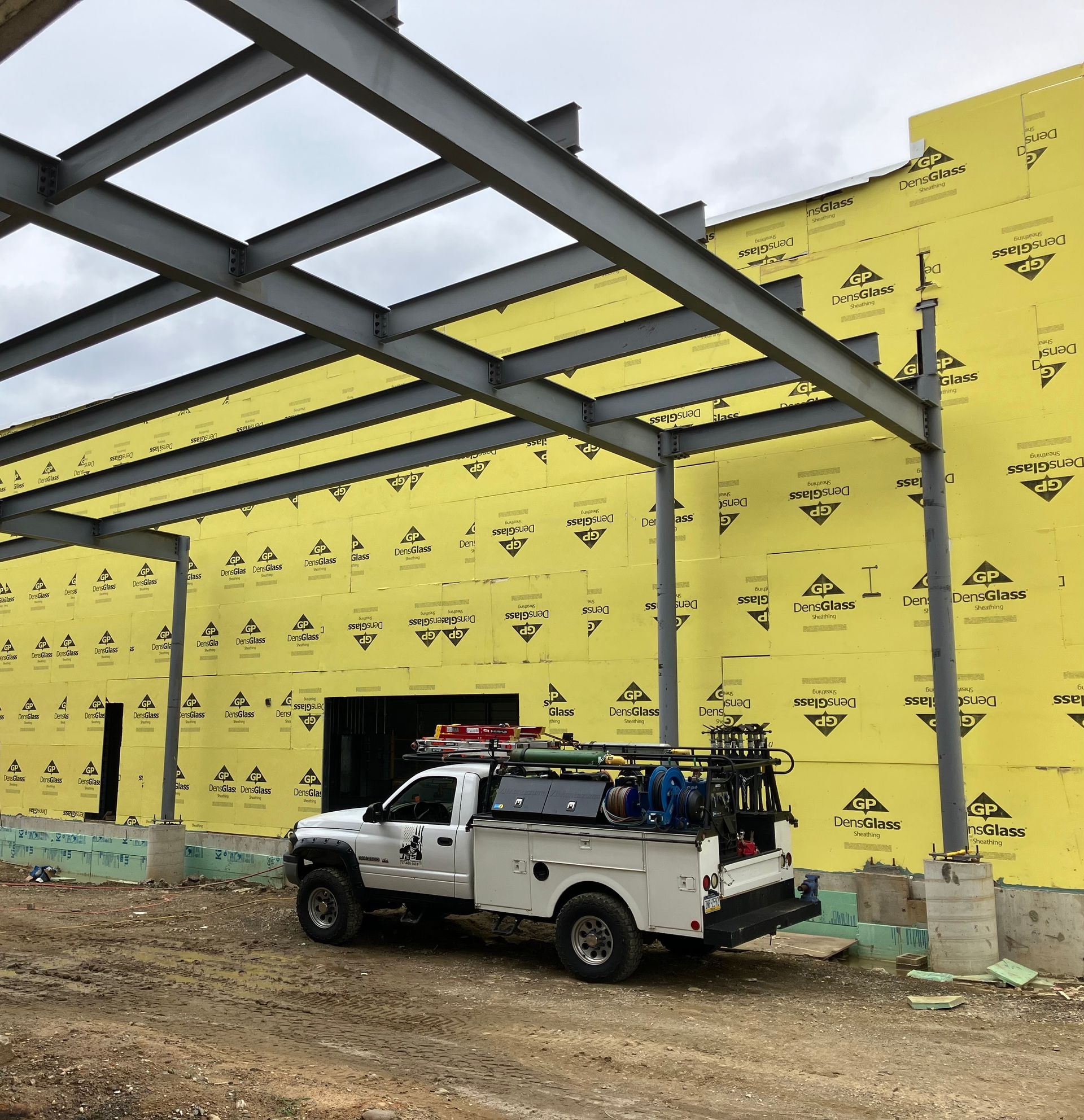 A white truck is parked in front of a building under construction
