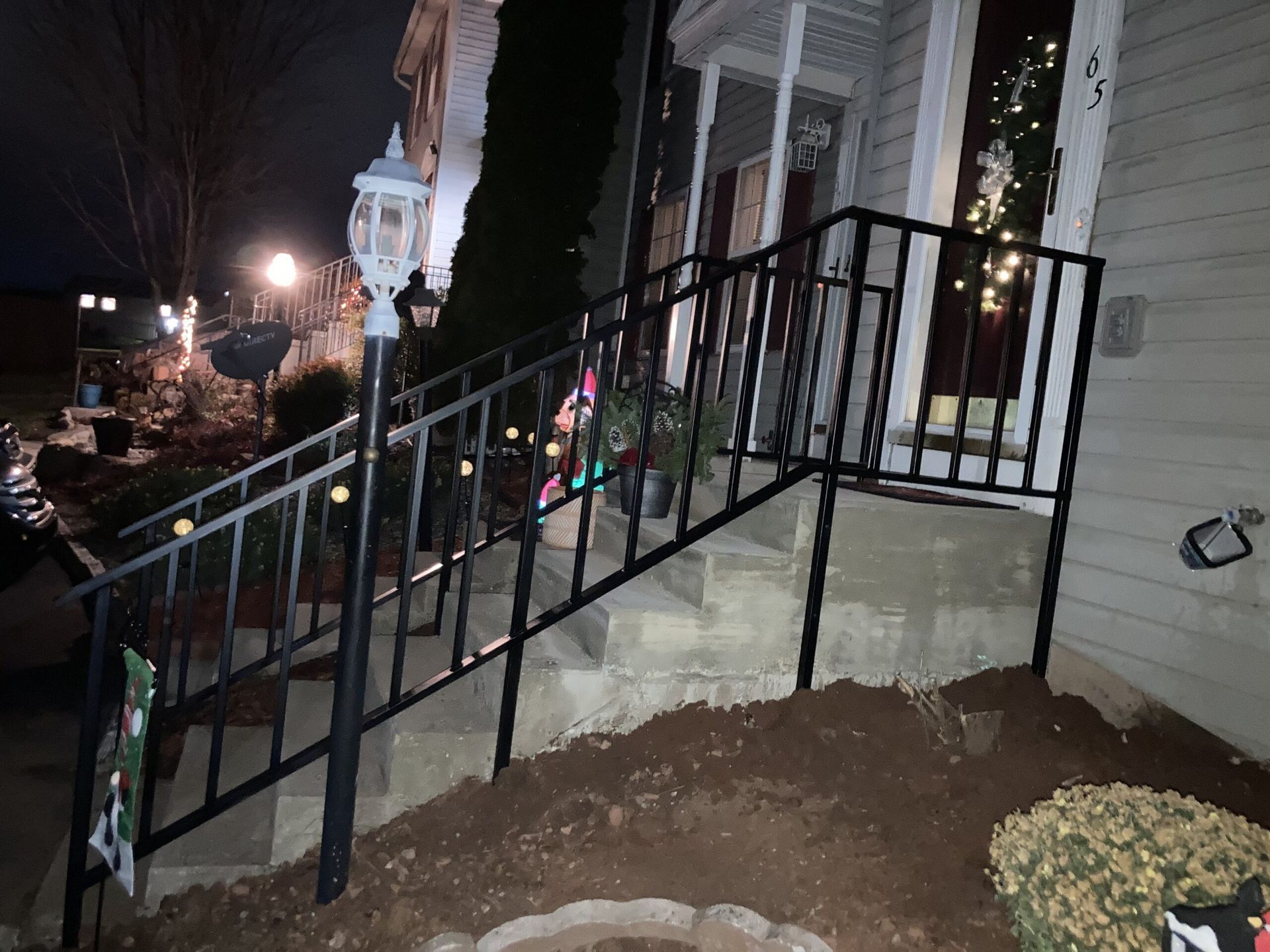 A wrought iron railing on the stairs of a house at night.