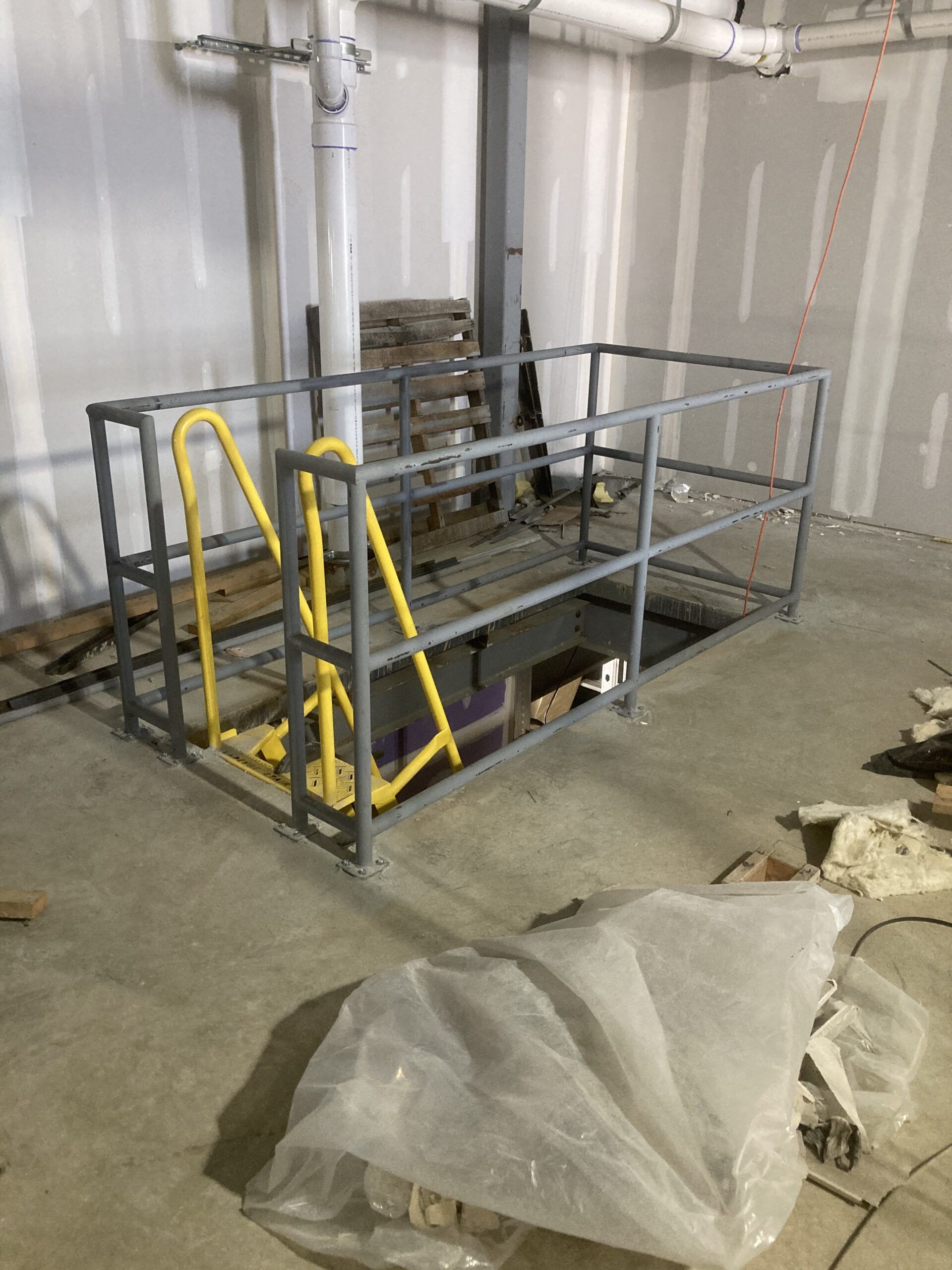 A metal staircase with a yellow railing in a room.