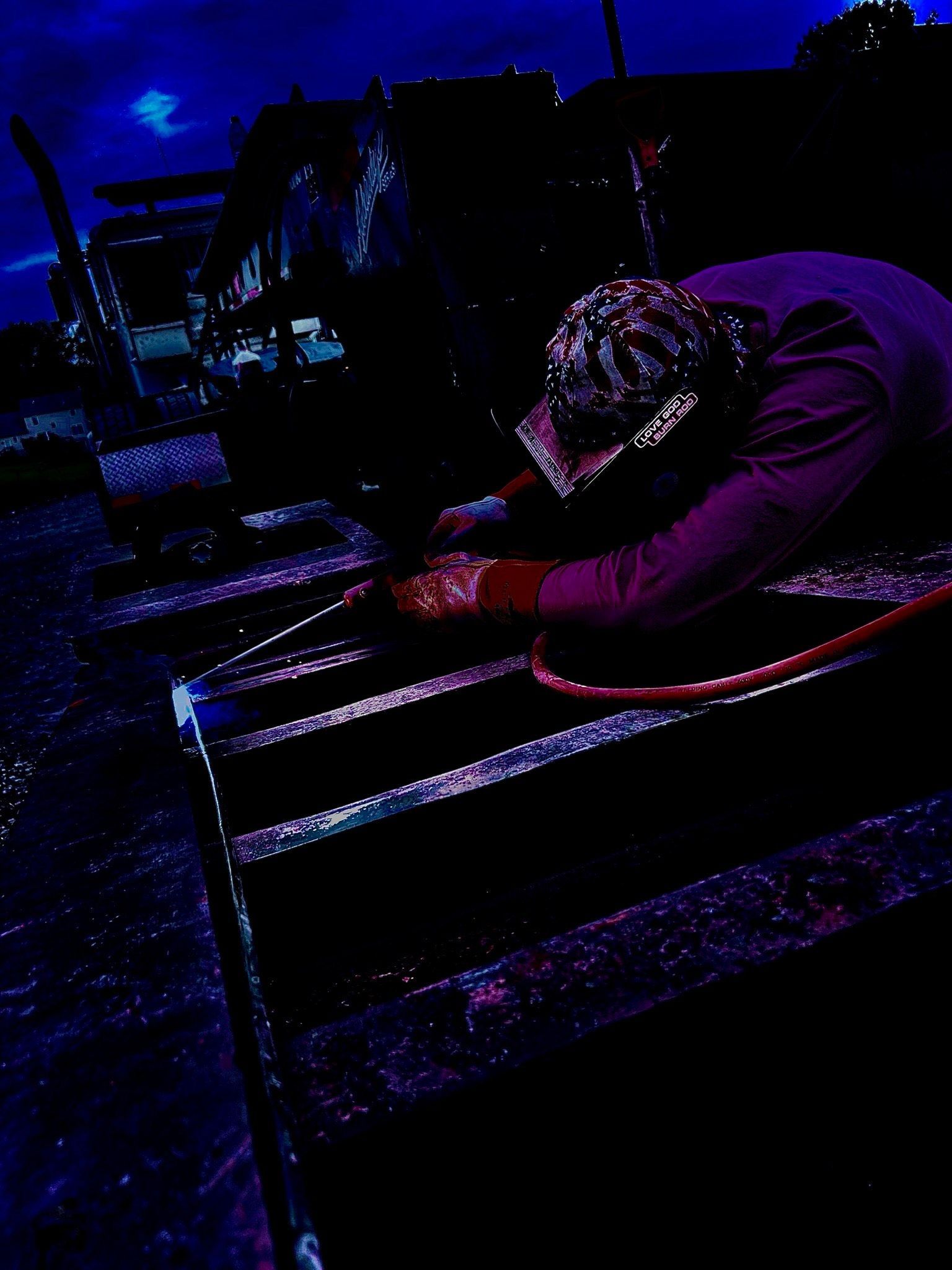 A man is welding a piece of metal in a dark room