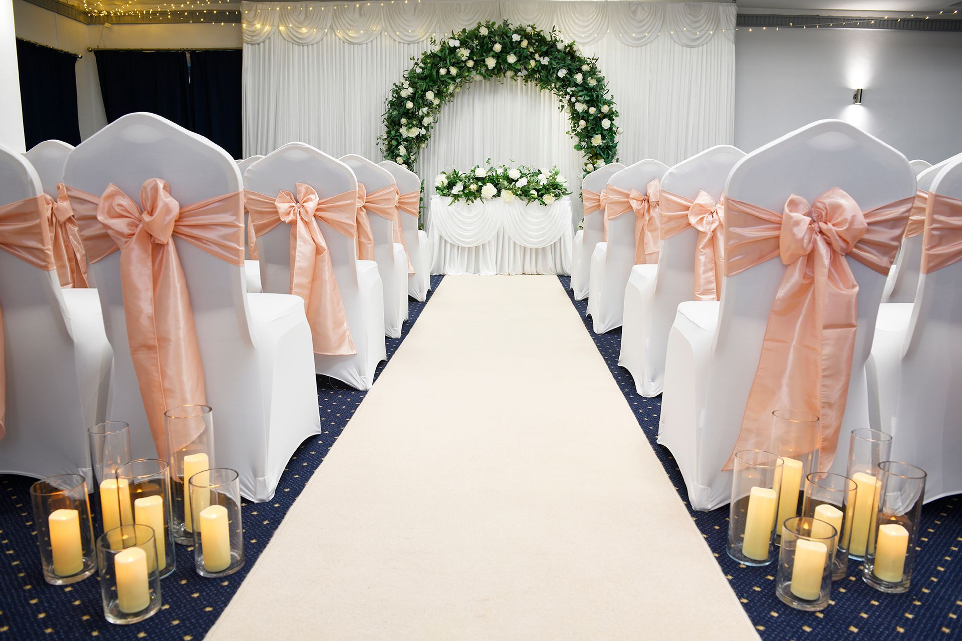 A wedding ceremony is being held in a room with chairs and candles.