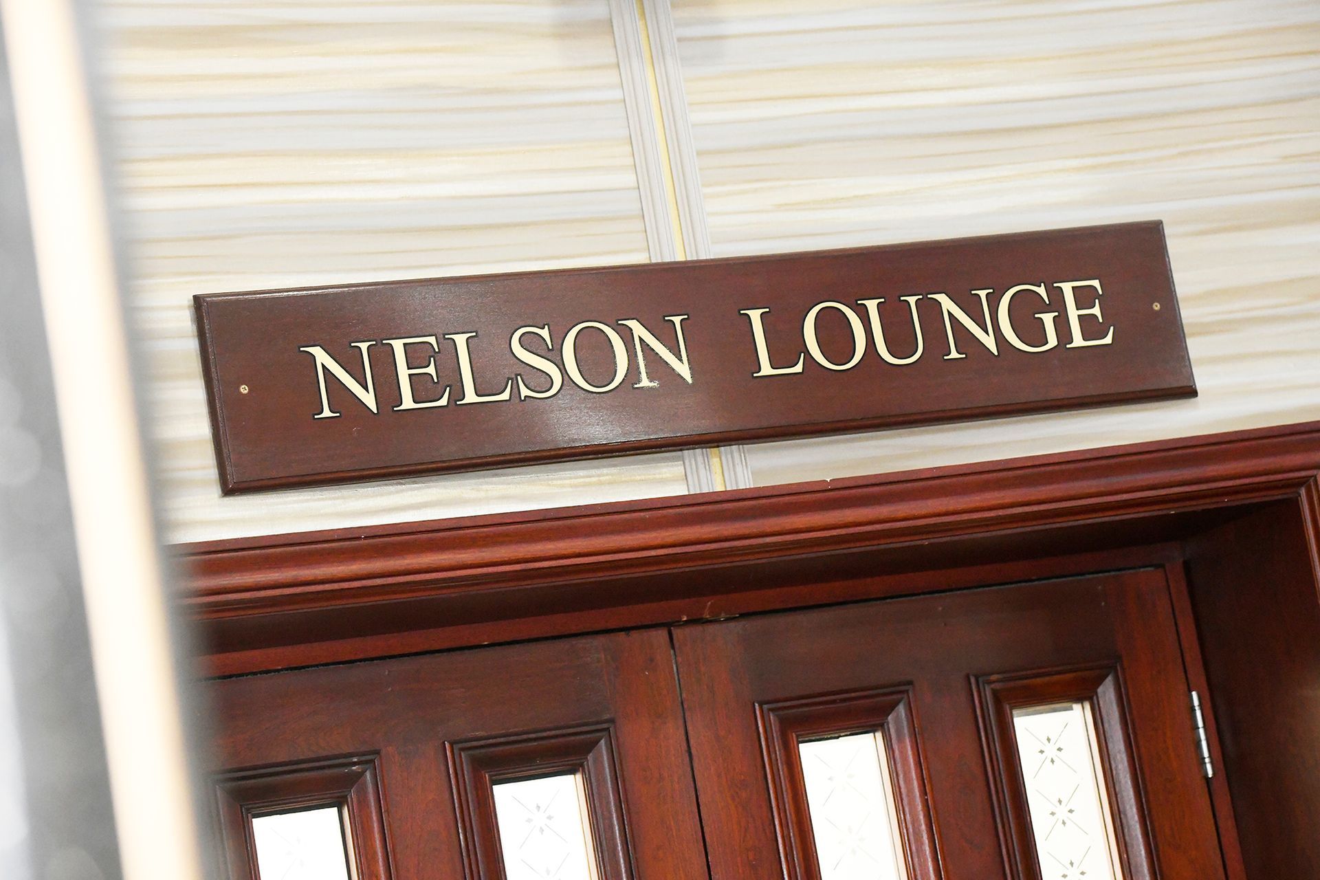 A wooden sign on a door that says nelson lounge