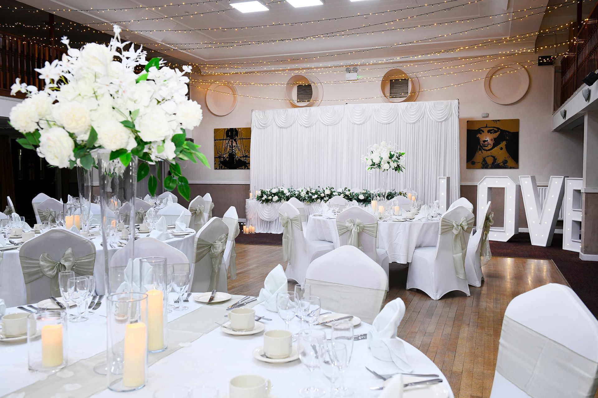 A large room with tables and chairs set up for a wedding reception.