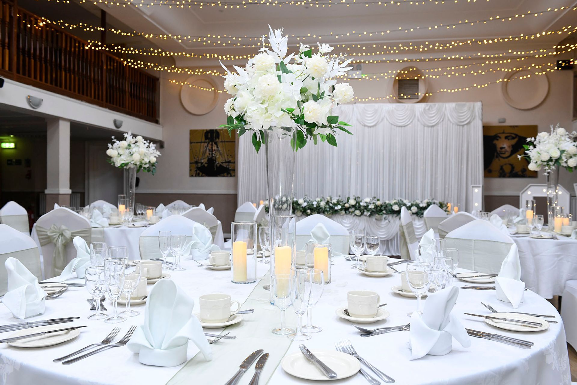 A room filled with tables and chairs set up for a wedding reception.