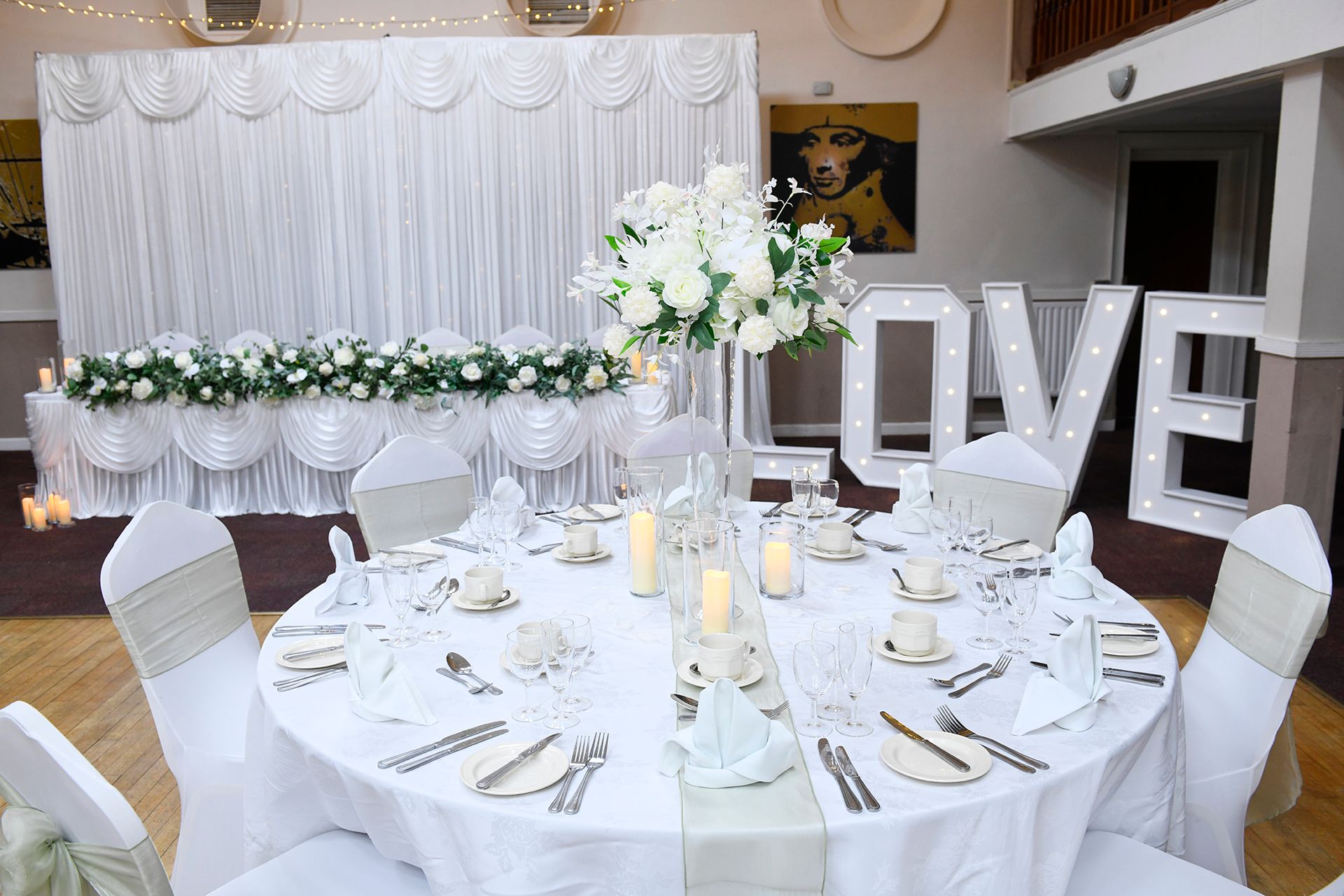 A table set for a wedding reception with a love sign in the background.