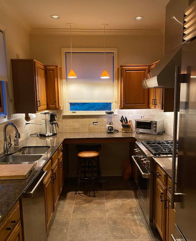 U-shaped kitchen with wooden cabinets, stainless steel appliances, and a breakfast bar.