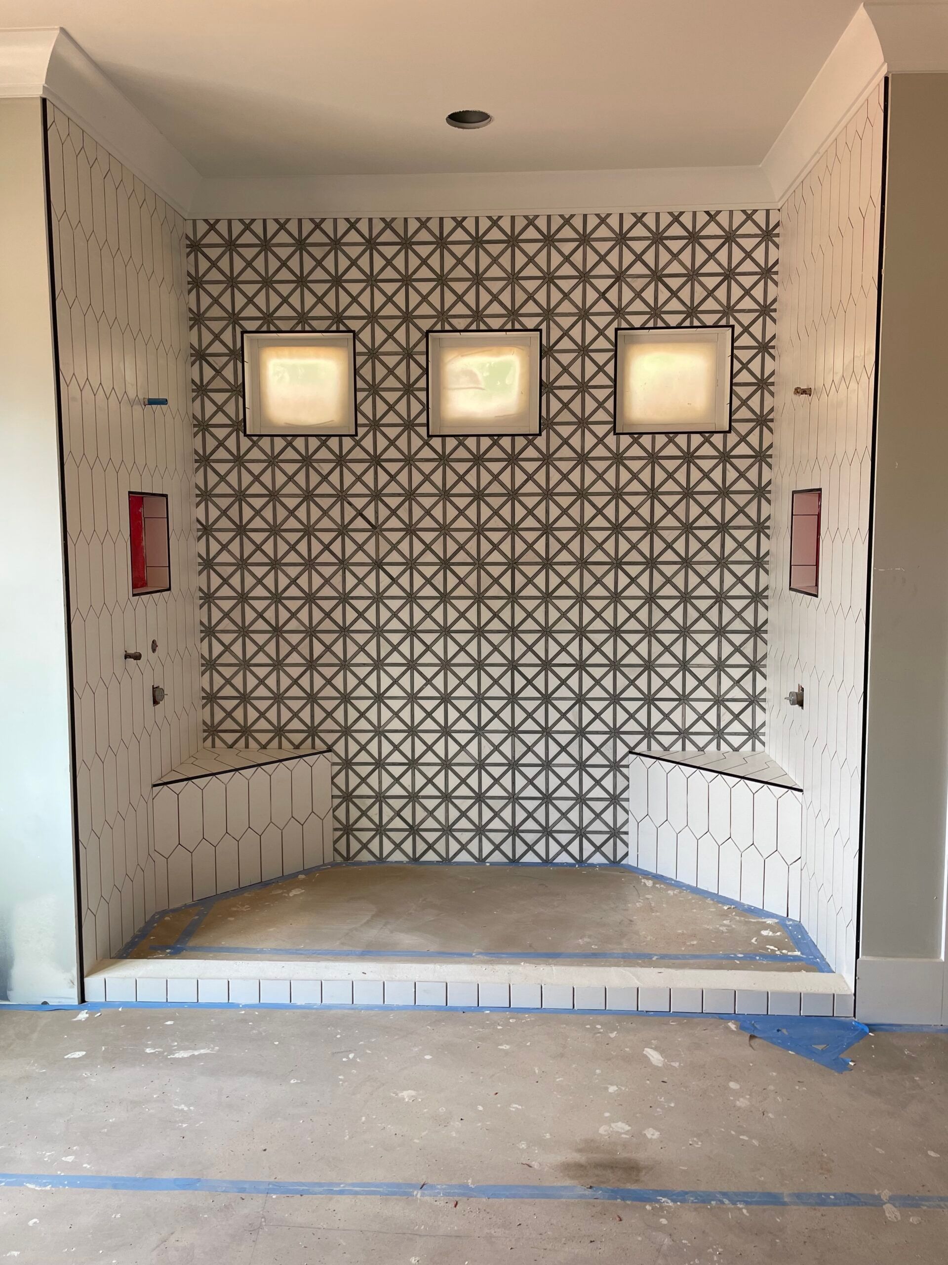 Bathroom shower under construction with tiled back wall, niche, and bench.