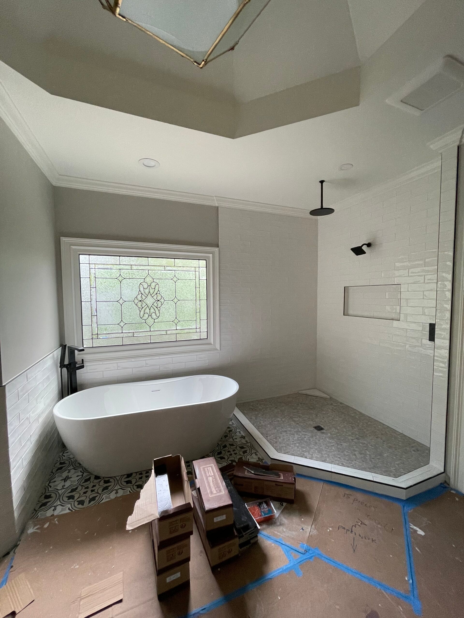 Bathroom under construction with a freestanding tub, shower, and window.
