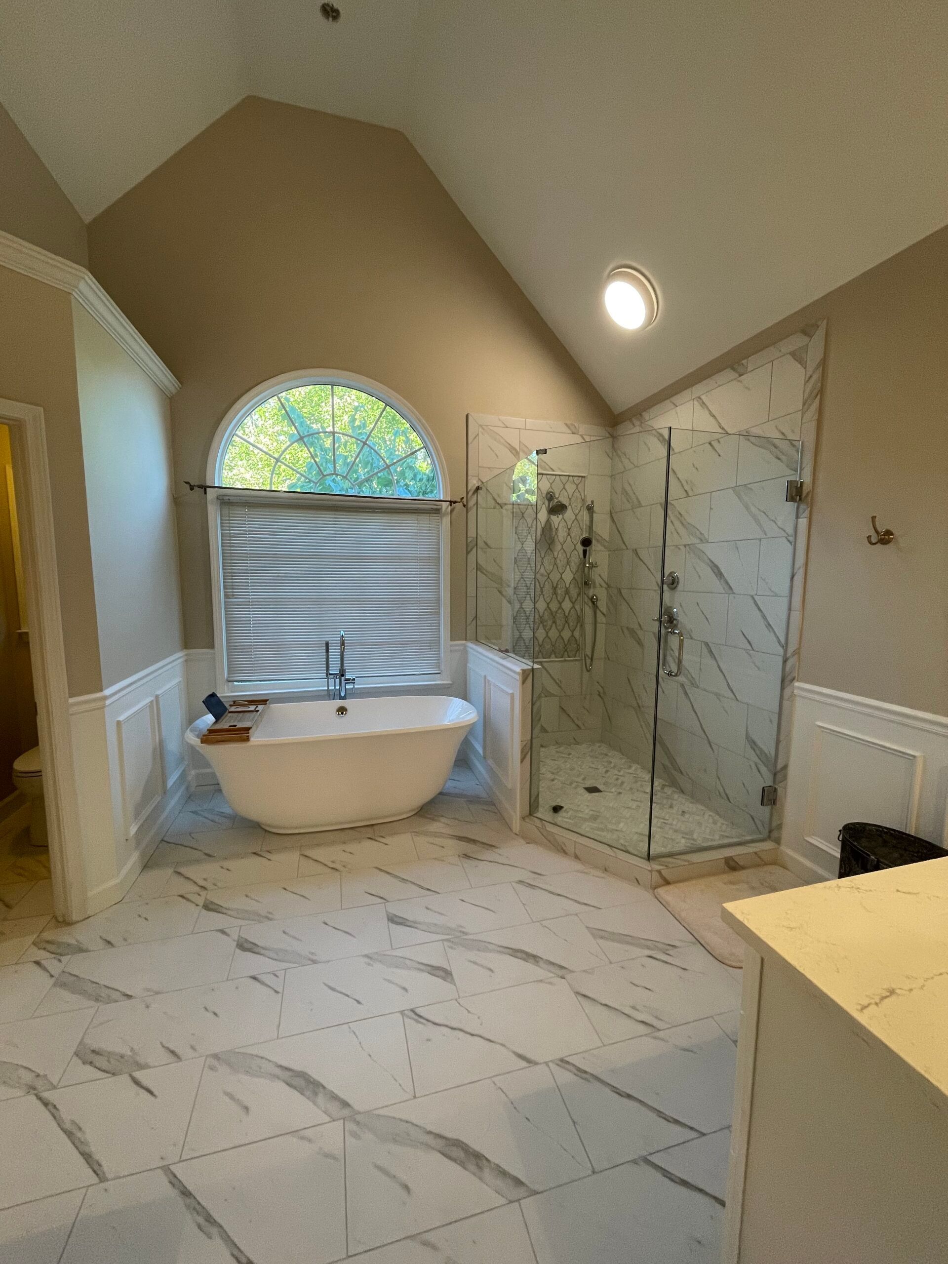 Spacious bathroom with freestanding tub, marble tile, and glass shower.