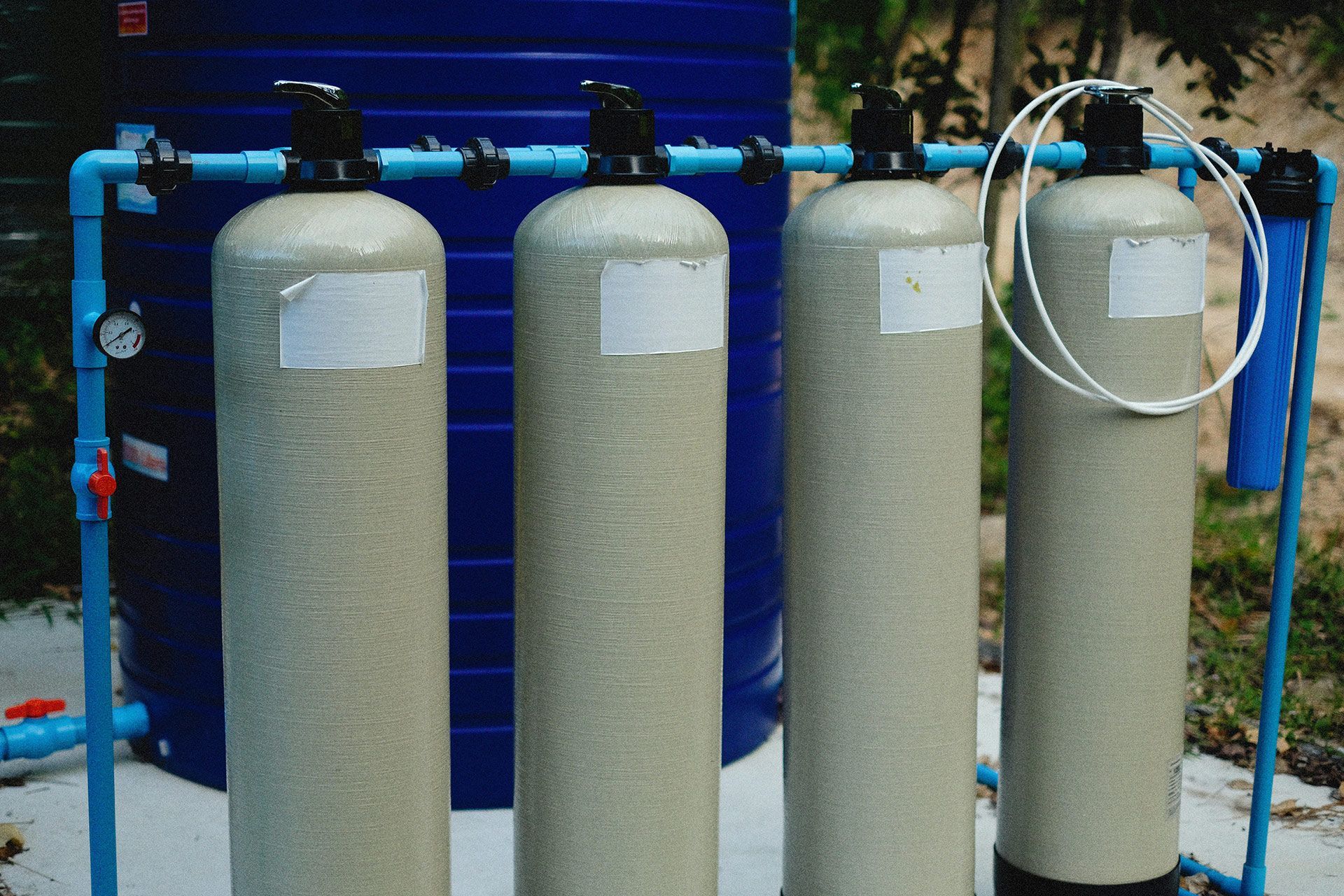 Water filtration system with four tall, cylindrical tanks and blue piping.