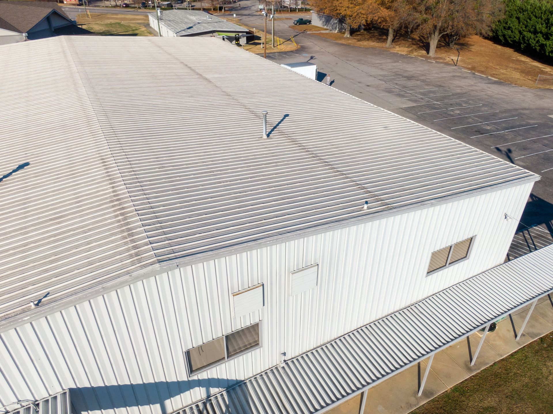 Aerial view of a white industrial building with a corrugated metal roof showing swirling patterns.