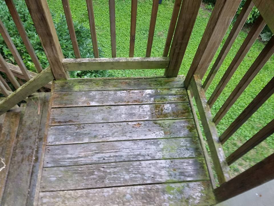 A wooden deck with a railing and stairs leading up to it.