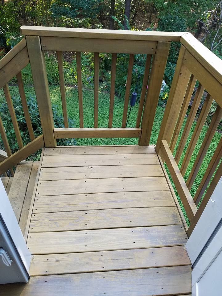 A wooden deck with a railing and stairs leading up to it.
