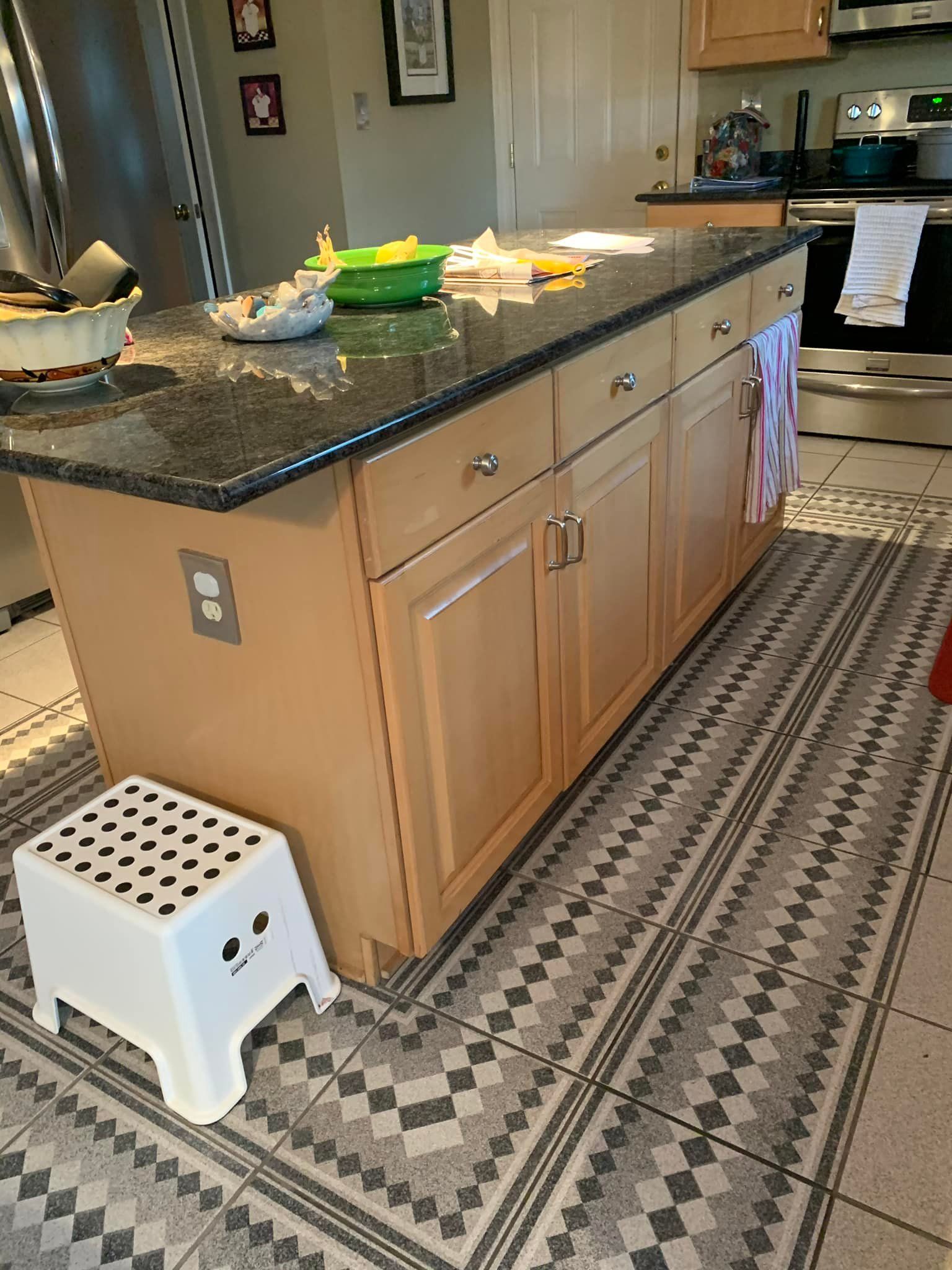 A kitchen island with a stool and a rug on the floor.